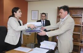 La jueza de Ejecución Sandra Kirchhofer entrega títulos de los inmuebles de Ramón González Daher y su hijo al funcionario de Senabico, Omar Parra.