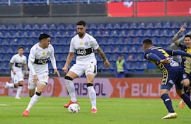 El delantero de Olimpia, Gabriel Ávalos intenta extender el pase para el extremo Bernardo Romeo Benítez.