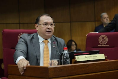 Ramón Retamozo con corbata, sentado en reunión legislativa, habla mientras otros lo observan.