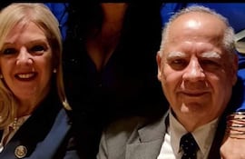 Benítez Riera con saco oscuro y broche, junto a su esposa Sienra Bertón con cabello rubio y saco oscuro, ambos sonrientes en un ambiente informal.