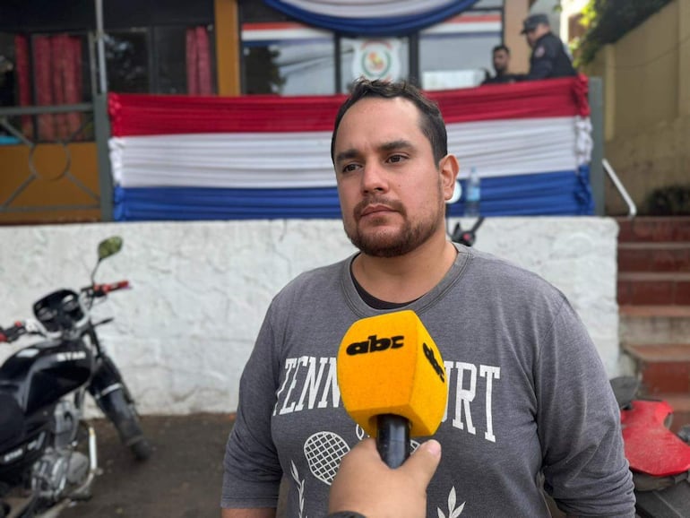 Daniel Miranda con barba y camiseta gris, siendo entrevistado, mientras un grupo de agentes y una motocicleta negra están en el fondo.