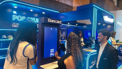Mujer de cabello largo y lacio con camiseta clara sonríe frente a una pantalla. Ambiente azul y blanco, elementos promocionales de Bancard.
