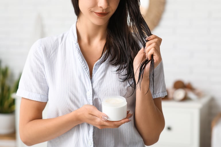 Mujer se aplica aceite de coco en el cabello.