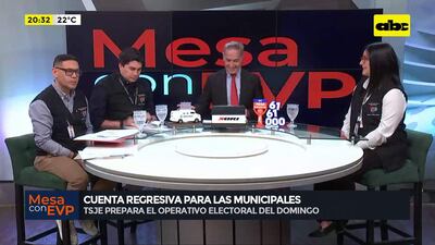 Cuatro personas discuten en un estudio de televisión; presentador canoso sonriente y participantes en chalecos negros observan atentamente.