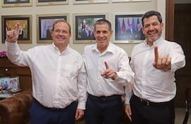 Camilo Pérez, Raúl Latorre y Horacio Cartes con camisas blancas y sonrisa, levantando el dedo índice en un fondo decorado formalmente.