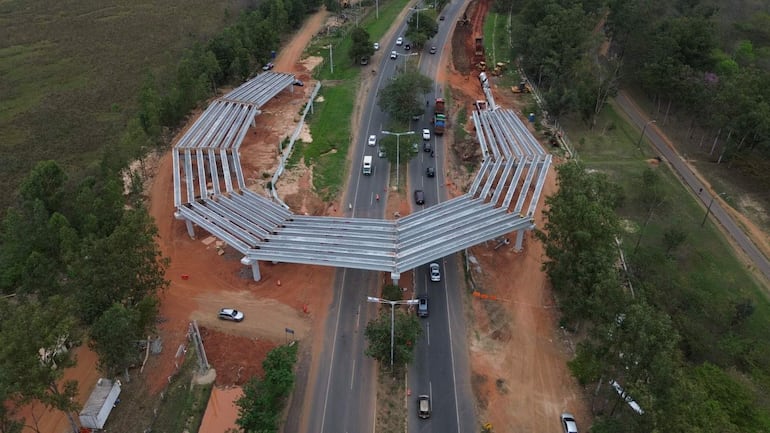 Vista aérea del viaducto de retorno en construcción sobre la autopista Silvio Pettirossi, rodeado de vegetación y tierra.