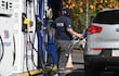 Empleado de Petropar en uniforme, sosteniendo una manguera de combustible frente a un Kia Sportage en una estación de servicio.