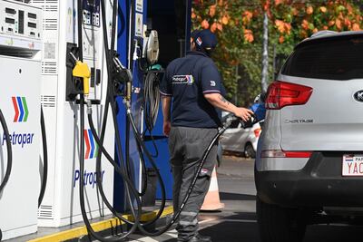 Empleado de Petropar en uniforme, sosteniendo una manguera de combustible frente a un Kia Sportage en una estación de servicio.