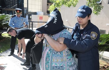 La funcionaria del Juzgado de Primera Instancia de San Lorenzo, Antonia Galeano, esposada, encapuchada y custodiada, tras su detención por presunta coima.