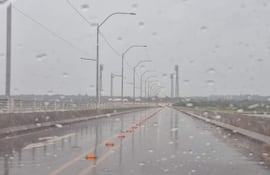 Carretera iluminada bajo la lluvia, sin personas visibles, con cielos nublados y ambiente desolador.