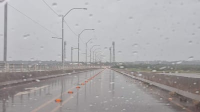 Carretera iluminada bajo la lluvia, sin personas visibles, con cielos nublados y ambiente desolador.
