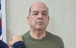 Miguel Ángel Robles de pie, con expresión seria y suéter verde oliva, mientras otro hombre lo toca levemente en el hombro.