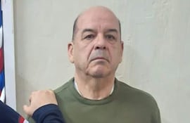 Miguel Ángel Robles de pie, con expresión seria y suéter verde oliva, mientras otro hombre lo toca levemente en el hombro.