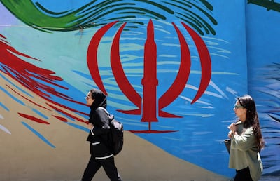 Ciudadanos iraníes pasan junto a un mural con la bandera nacional de Irán en una calle de Teherán, Irán.