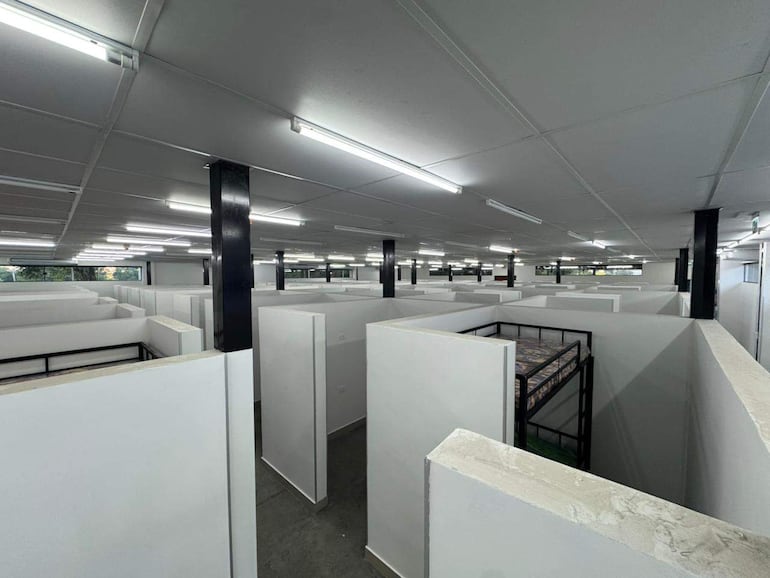 Espacio interior vacío con divisiones de paredes blancas, luz artificial y sin decoración visible.