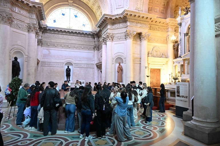 Grupo de personas reunidas en un altar, algunas con expresiones de tranquilidad y atención a un guía que habla.
