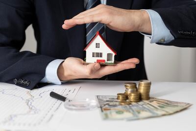 Manos protegiendo una casa en miniatura: Concepto de seguro de hogar y protección financiera.