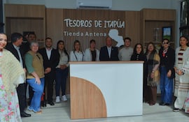 Grupo de 12 personas sonríen en inauguración, con vestimenta tradicional y formal en ambiente festivo.