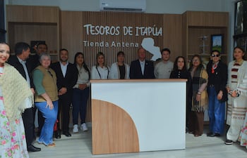 Grupo de 12 personas sonríen en inauguración, con vestimenta tradicional y formal en ambiente festivo.