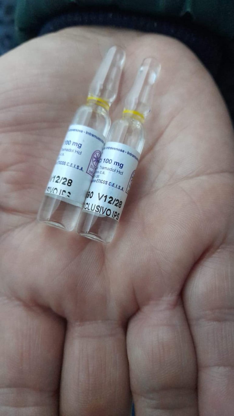 Una mano sostiene dos ampollas transparentes, etiquetadas con información sobre Tramadol HCl y su contenido.
