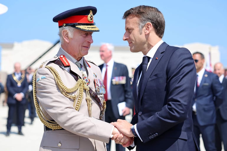 El presidente de Francia, Emmanuel Macron (d) saluda al rey Carlos III durante la conmemoración del "Día D".