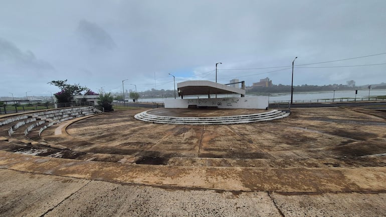 Espacio vacío del anfiteatro a orillas del río, con gradas semicirculares y cielo nublado que presagia lluvia.