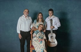 Kattya González sentada con atuendo tradicional, flanqueada por Margarita Irún y un joven con guitarra en fondo azul.