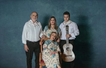 Kattya González sentada con atuendo tradicional, flanqueada por Margarita Irún y un joven con guitarra en fondo azul.