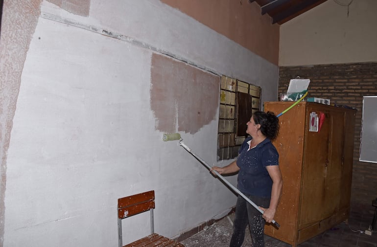 La profesora Jacquelin Morel, pinta su grado con cal, sin presupuesto para comprar pintura. Entre labores, se torció el tobillo.