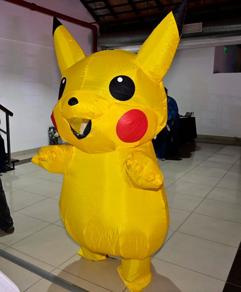 Disfraz inflable de Pikachu en un evento con fondo de mesas y asistentes indistintos, destacando en un ambiente interior.