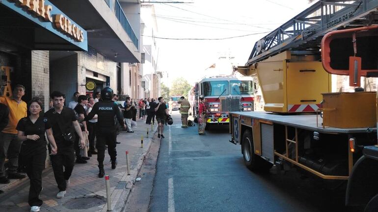 Agente de policía con uniforme y bomberos interactuando con el público en la calle General Díaz, durante un incidente de incendio.