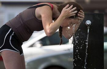 Una mujer se refresca luego de realizar actividades físicas en un parque de Asunción.
