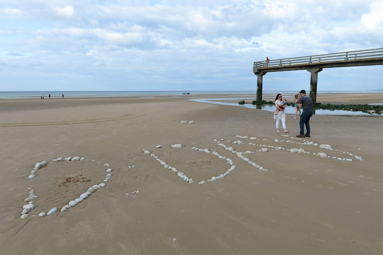 Fotografía de archivo: una familia se encuentra junto a la palabra “D-Day”, escrita con piedras en la playa de Omaha, en Vierville-sur-Mer, noroeste de Francia, durante los preparativos de las celebraciones por el 75.º aniversario del desembarco del Día D.