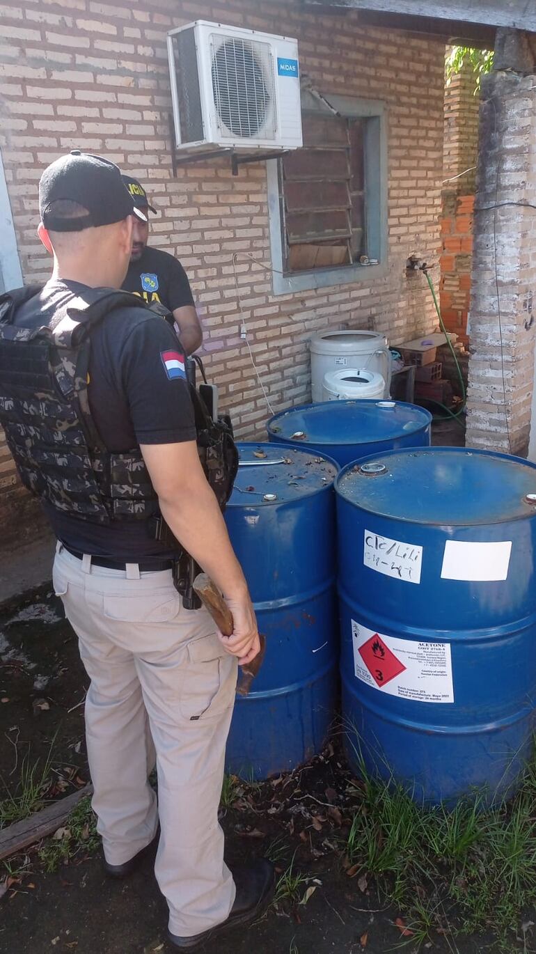 Los oficiales intervinientes en el procedimento verifican los tambores, uno de ellos cargado supuestamente con acetona, que también fueron encontrados en el mismo sitio.