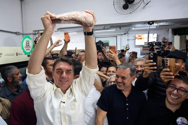 El candidato presidencial de derecha y senador Flavio Bolsonaro muestra un trozo de carne en un mercado municipal de São Miguel Paulista, distrito de São Paulo, Brasil, el 20 de agosto de 2026. (Photo by Miguel SCHINCARIOL / AFP)