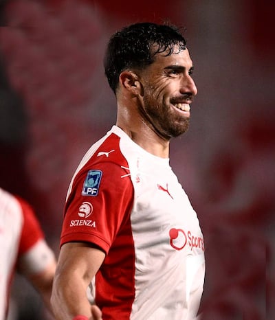 Gabriel Ávalos sonríe luciendo camiseta blanca con detalles rojos, en un ambiente de celebración deportiva en el estadio.