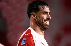 Gabriel Ávalos sonríe luciendo camiseta blanca con detalles rojos, en un ambiente de celebración deportiva en el estadio.