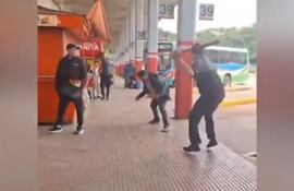 Uno de los choferes amaga ensayar un golpe con un palo, mientras el otro se agacha para esquivar.