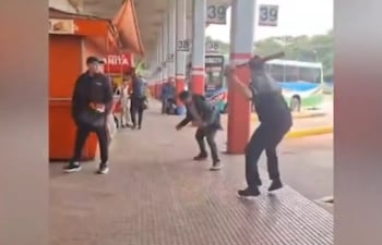 Uno de los choferes amaga ensayar un golpe con un palo, mientras el otro se agacha para esquivar.