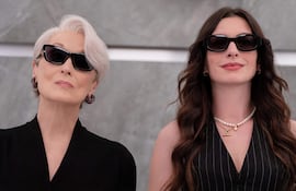 Anne Hathaway con cabello corto y prenda negra, y Meryl Streep con blusa a rayas y collar de perlas, ambas con gafas oscuras.
