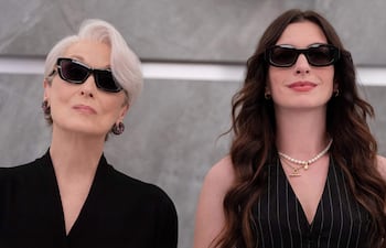 Anne Hathaway con cabello corto y prenda negra, y Meryl Streep con blusa a rayas y collar de perlas, ambas con gafas oscuras.