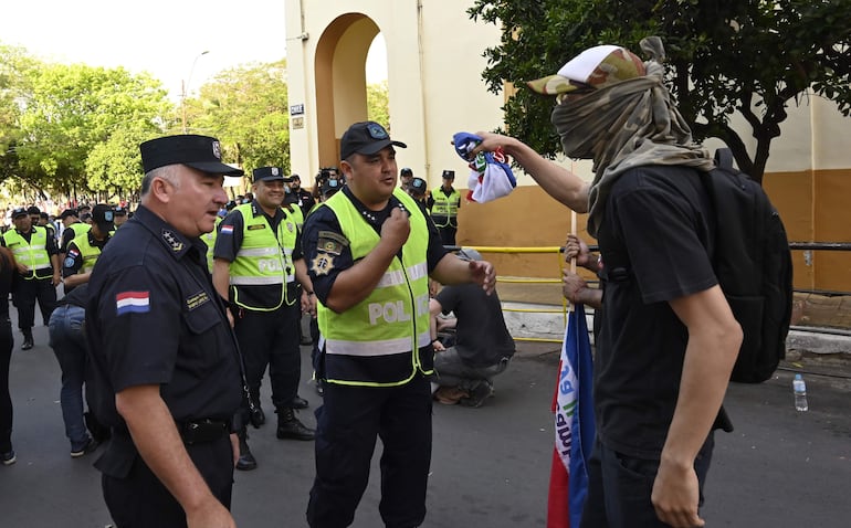 Una persona enmascarada increpa a dos policías durante la manifestación de la generación Z.