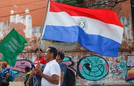 AME4650. ASUNCIÓN (PARAGUAY), 10/12/2024.- Un hombre sostiene una bandera durante una manifestación en el Día Internacional de los Derechos Humanos este martes, en Asunción (Paraguay). El "cierre" de los espacios de debate político con la participación de la sociedad civil fue el reclamo que aglutinó este martes a diversas organizaciones sociales que marcharon para alertar sobre un supuesto retroceso de la democracia en Paraguay. EFE/ Juan Pablo Pino