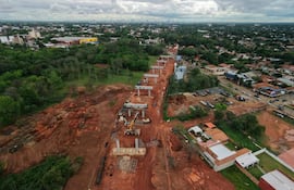 Vista aérea de la construcción de la autopista elevada en Luque, con maquinaria y cimientos visibles entre un entorno suburbano.