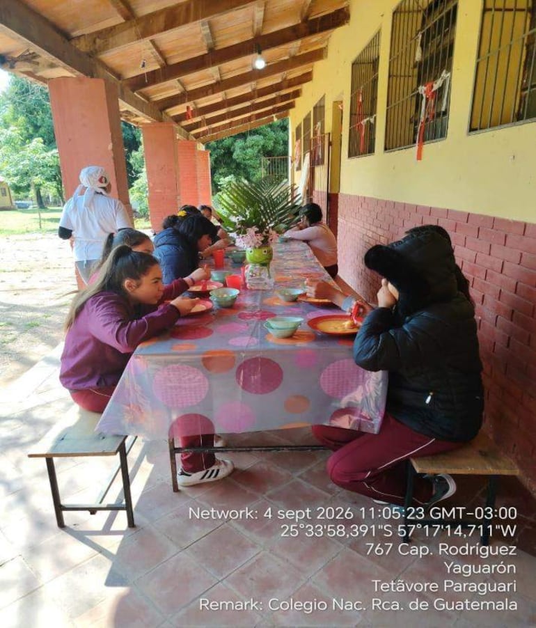 Grupo de jóvenes sentados alrededor de una mesa decorada y colorida, interactuando con comida en un ambiente fresco.