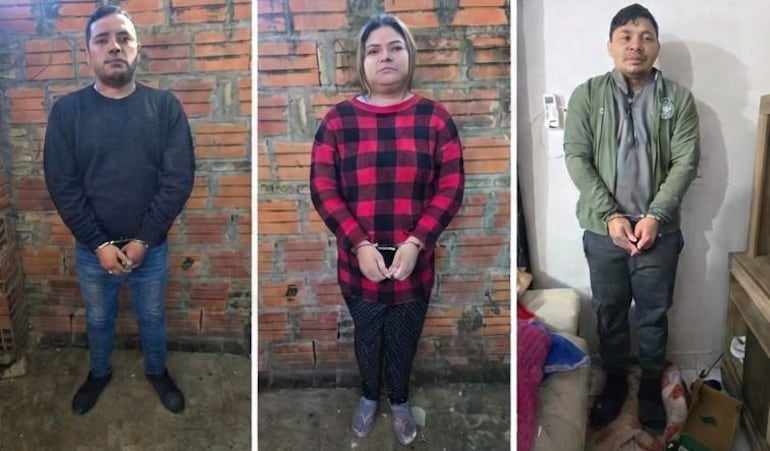 Tres detenidos esposados: hombre con suéter negro, mujer en camiseta de cuadros rojos y negros, hombre con chaqueta verde, en ambiente interior.