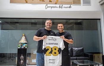 El presidente de Olimpia, Rodrigo "Coto" Nogués y el volante Hugo Quintana sostienen la camiseta franjeada, tras rubricar la extensión de contrato del excelente mediocampista.
