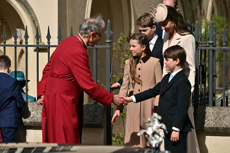 El decano de Windsor, Christopher Cocksworth, estrecha la mano del príncipe Louis mientras la princesa Charlotte, el príncipe George y la princesa de Gales Kate Middleton salen de la capilla de San Jorge, en Windsor, al oeste de Londres. (Ben STANSALL / AFP)