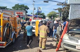 Bomberos en trajes de intervención rodean un vehículo accidentado en Villa Elisa, mientras varios observadores toman fotos.