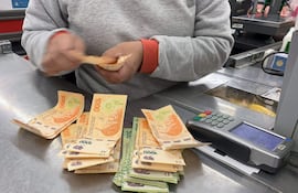 Cajero cuenta pesos argentinos en un comercio.
